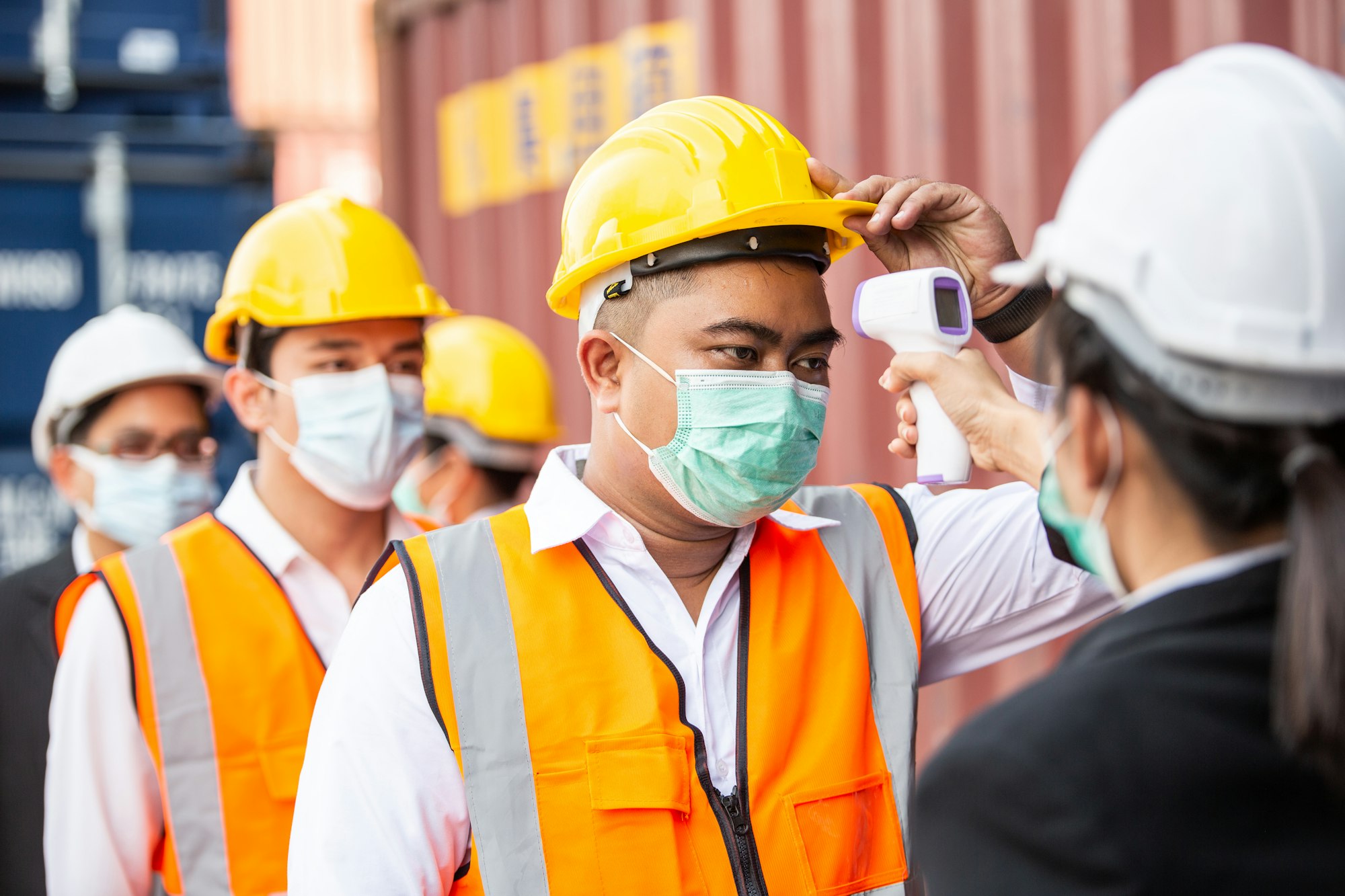 Female worker scanning fever temperature with digital thermometer